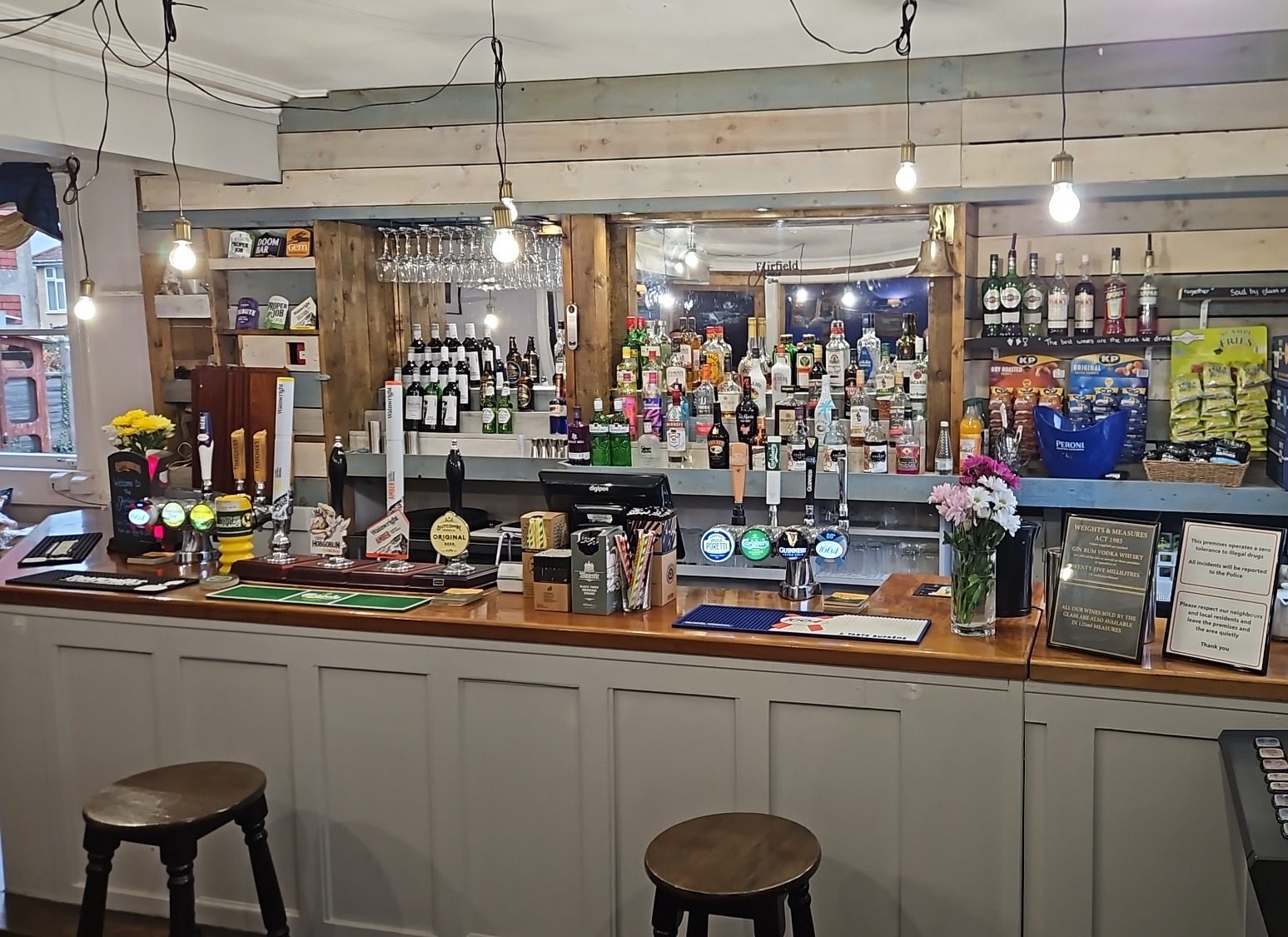 Bar area with wooden plank back bar, painted pastel blue, grey, and white.